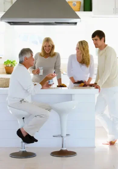 A family of four talking and smiling around a white kitchen island
